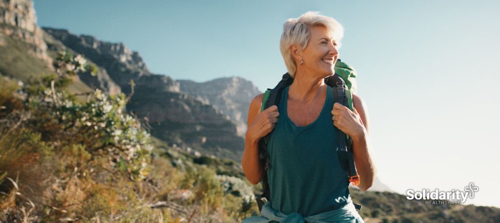 A healthy middle aged woman hikes in the mountains with a backpack